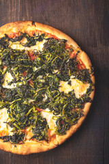 Neapolitan Italian pizza with wild broccoli or turnip greens or Friarielli ( broccoletti  Romani, broccoli di rapa in Calabria, cime di rapa in Puglia ), smoked provola cheese on a wooden  rustic back