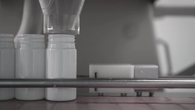 rellenar envase blanco de pl&aacute;stico con c&aacute;psulas o medicamentos farmac&eacute;uticos con maquina industrial en empresa de la industria farmac&eacute;utica