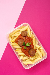 Macaroni with tomato sauce, chorizo and cheese in plastic container