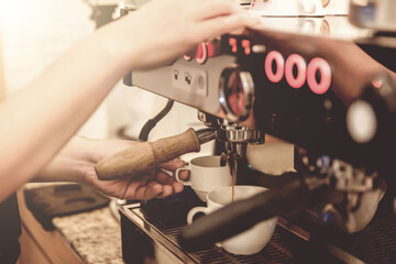 Close-up of barista hand holding coffee cup using coffee machine in bar