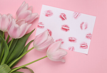 Lip print left by lipstick on white paper and tulips on pastel purple background. Valentine's day concept. Top view