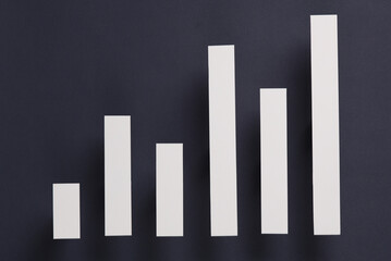 Paper-cut columns of a chart tending upwards on a gray background. Economic growth, analytics, business concept