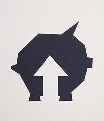 Paper-cut hole in the shape of a piggy bank and growth arrow on a gray background. Business concept