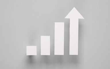Paper-cut columns of a chart tending upwards on a gray background. Economic growth, analytics, business concept