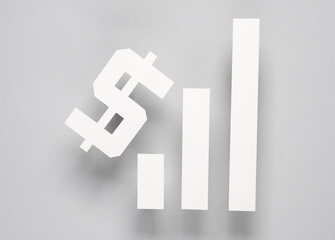 Paper-cut columns of a chart tending upwards and dollar symbol on a gray background. Analytics, business concept