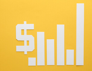 Paper-cut columns of a chart tending upwards and dollar symbol on yellow background. Analytics, business concept