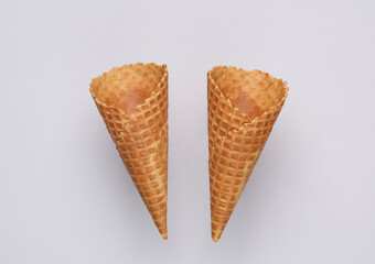 Two empty waffle cones on a gray background