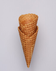 Two empty waffle cones on a gray background