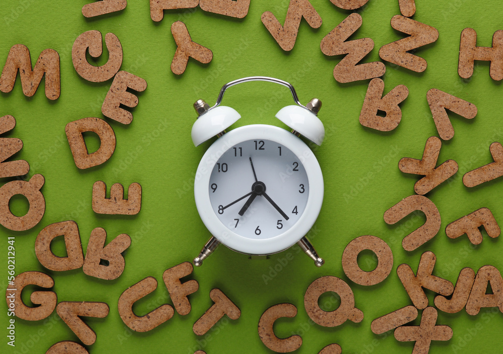 Wall mural Alarm clock with wooden letters on a green background