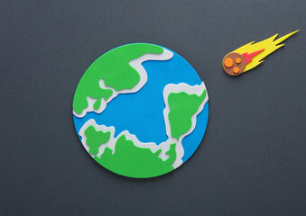 Handmade, children's art. Planet earth with a flying meteorite on a gray background.