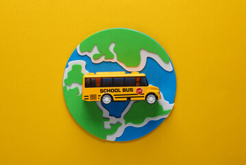 Planet earth with a school bus on yellow background. Education, travel concept