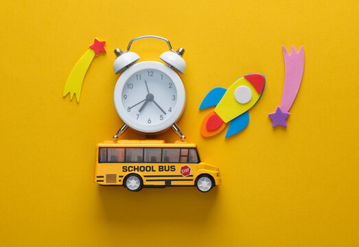 Toy school bus with rocket and alarm clock on a chalkboard. Back to school. Education concept