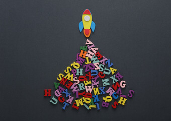 Toy ocket and letters on gray background. Back to school. Education concept. Flat lay