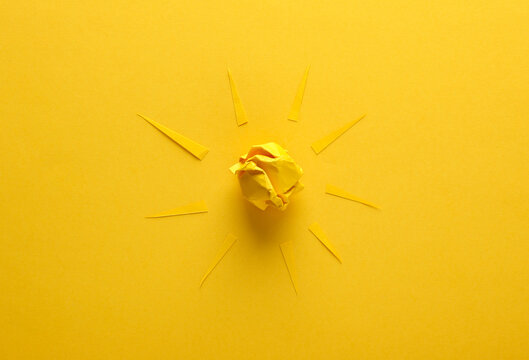 Paper sun with rays on yellow background