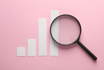 Bar chart with magnifier on pink background. Business concept