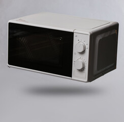 Modern microwave oven levitating on gray background with shadow