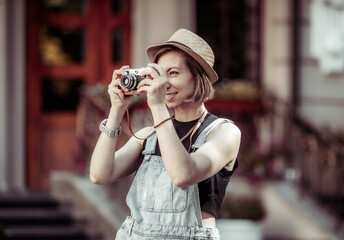 young hipster woman in denim overalls with retro camera in the city