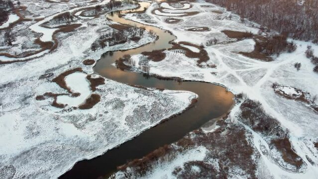 Look down winter aerial view on snowy river valley in golden sunset colors. Zmiyevsky region on Siverskyi Donets river, Ukraine