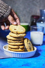 Coffee bean jar, hand holding homemade tasty cookies and milk bottle and cup