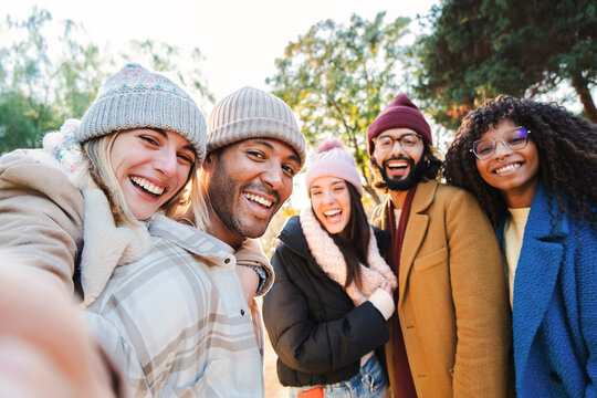 Group of young people smiling and having fun taking selfie portrait. Five multiracial happy friends looking at camera. Funny outdoor activity of cheerful students away from home. Lifetyle concept