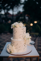 beautiful wedding cake with white roses in the background on a blurred of a restaurant
