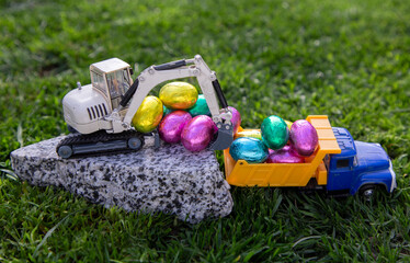toy excavator and dump truck with colorful chocolate eggs. Easter greetings, postcard. concept of business congratulations on easter holiday for construction companies