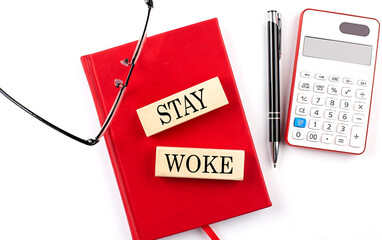 STAY WOKE text on wooden block on red notebook