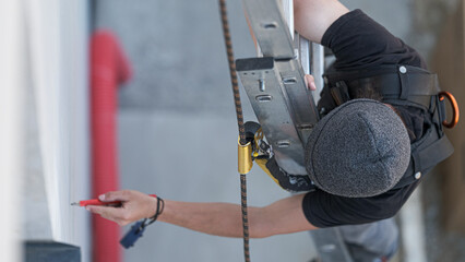 an electrical engineer of the team installs the electrical cables for the autonomous photovoltaic solar panel system. It is installed on a scale and uses a meter and a pencil for position measurements