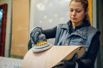Woman carpenter using an electric sander in a workshop or factory