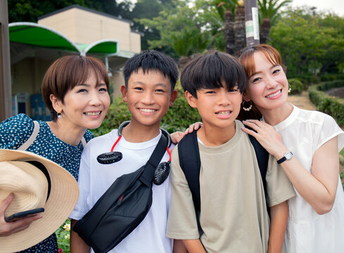 Four Japanese people on a outing, two mature women and two 13 year old boys, in a row, laughing.