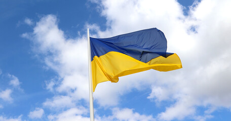 yellow and blue flag of Ukraine and sky with clouds in background