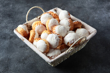 A basket with cupcakes on a gray background. Cupcakes in large quantities are in basket. White icing on cupcakes. Baking for the Easter holiday.