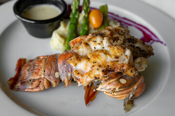 Close up detailed view of a grilled lobster tail on a white plate