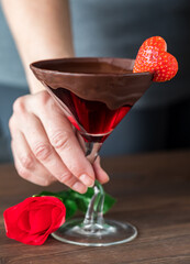 A hand holding a chocolate rimmed Valentine's Day cocktail in a martini glass.