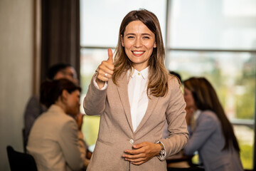 Obraz premium portrait of a young female team leader smiling with her co-workers in the background
