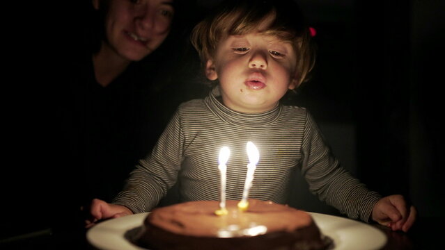 Baby toddler blowing birthday candles celebration. Two year old child blows candle