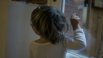 Fototapeta premium Child boy standing by window pointing at something outside