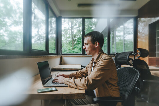 Young businessman working in office looking at laptop