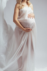 Close-up Elegant pregnant young woman standing wearing light fabric. Pregnancy, fantasy and fairy...