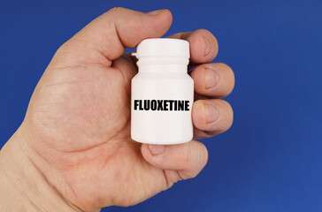 On a blue background in the hands of a man is a white jar with the inscription - Fluoxetine