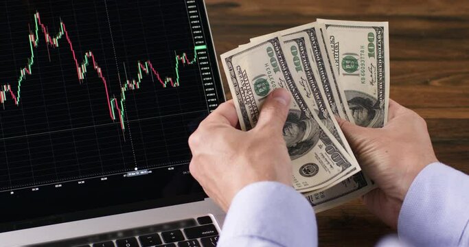 Financial investments in growing indices. Selecting the latest cache attachment. Dollars in the hands of a man against the background of a chart of the exchange rate trend.