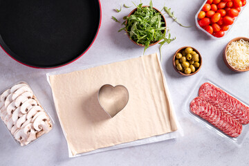 Making of mini pizzas in a heart shape for Valentines day holiday.
