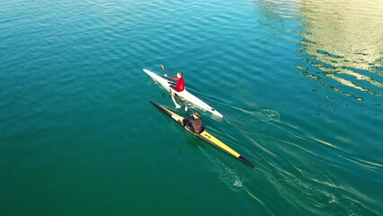 Aerial drone video of athletes competing in canoe race in tropical lake with emerald waters
