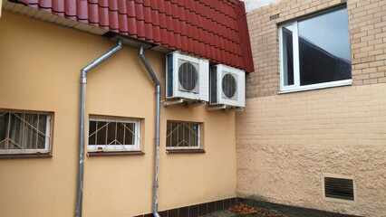 Under the roof of metal roof over the windows with louvers on the wall of the building on metal supports are installed air conditioners to create a microclimate inside the building. 