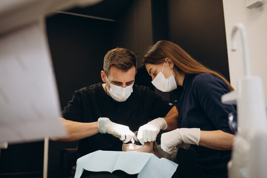 Painkiller anesthesia injection. Dentist examining a patient's teeth in modern dentistry office. Closeup cropped picture with copyspace. Doctor in disposable medical facial mask.