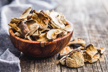 Sliced dried mushrooms in bowl on wooden table.