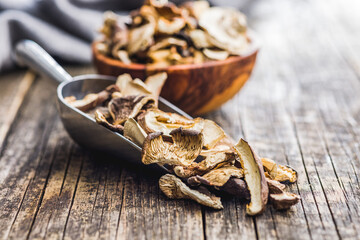 Sliced dried mushrooms in scoop on wooden table.