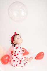 baby with valentine's heart shaped balloons
