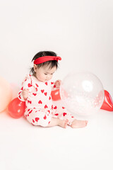 baby with valentine's heart shaped balloons