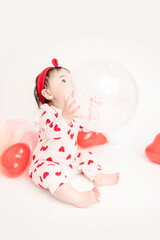 baby with valentine's heart shaped balloons